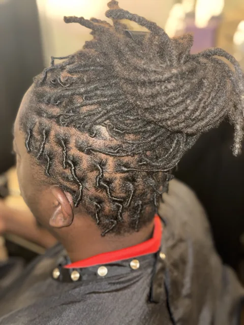 Side view of long locs gathered up with neatly defined roots at September’s Locs