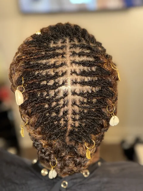 Back view of locs swept together with gold and shell accents at September’s Locs