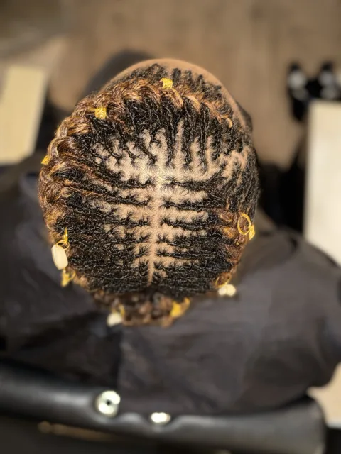 Top view of a sculpted loc style with decorative accents at September’s Locs