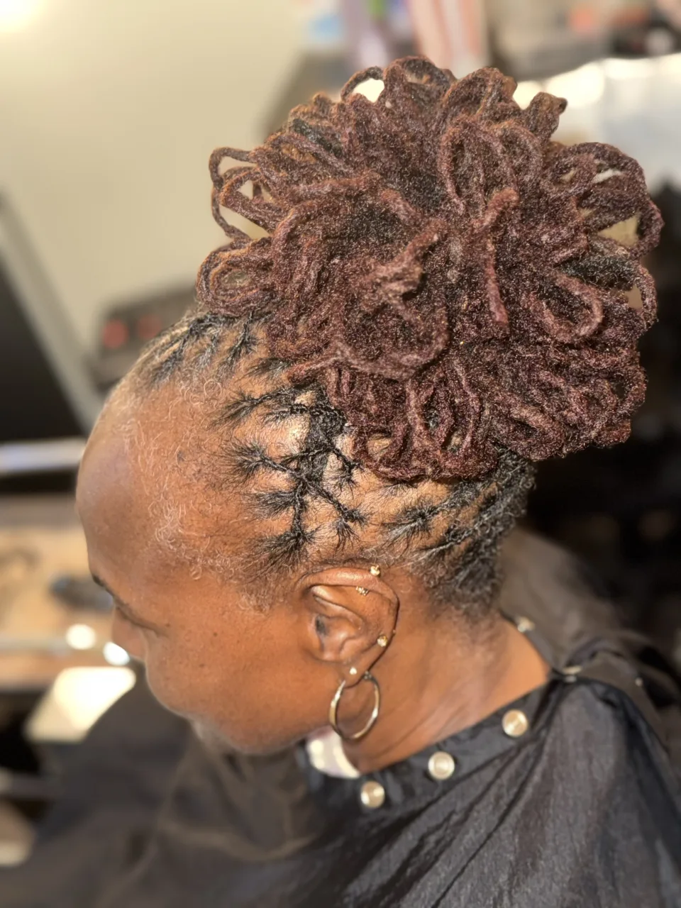 Sculpted loc updo with burgundy lengths and carefully parted roots at September’s Locs